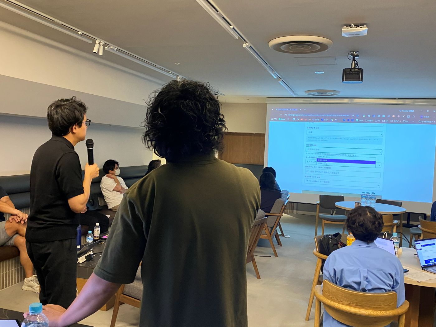 スクリーンの前で成果を発表する様子